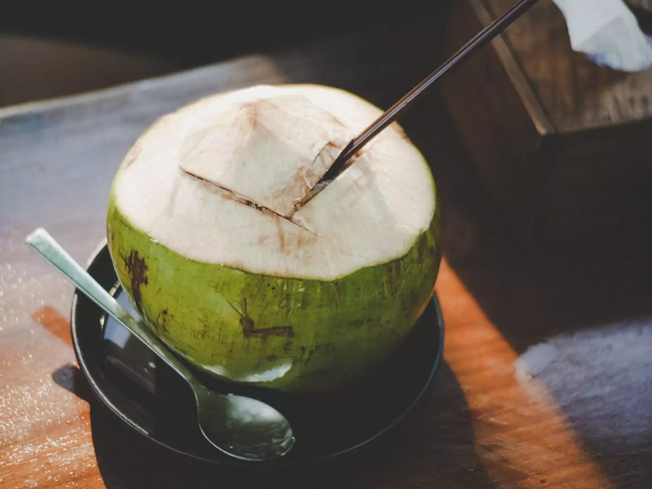 Um coco aberto com um canudo.