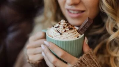 Mulher tomando um chocolate quente com chantilly.