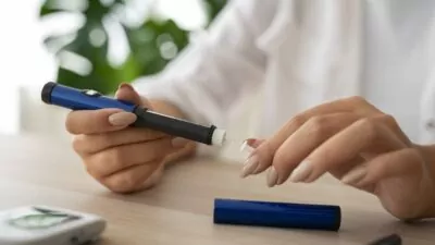 Em destque, mãos femininas manipulam uma caneta de Ozempic