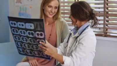 Médica mostra imagens de exames das mamas a uma paciente durante uma consulta.